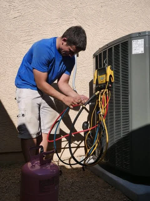 Technician connecting service hoses and gauges to a residential air conditioner